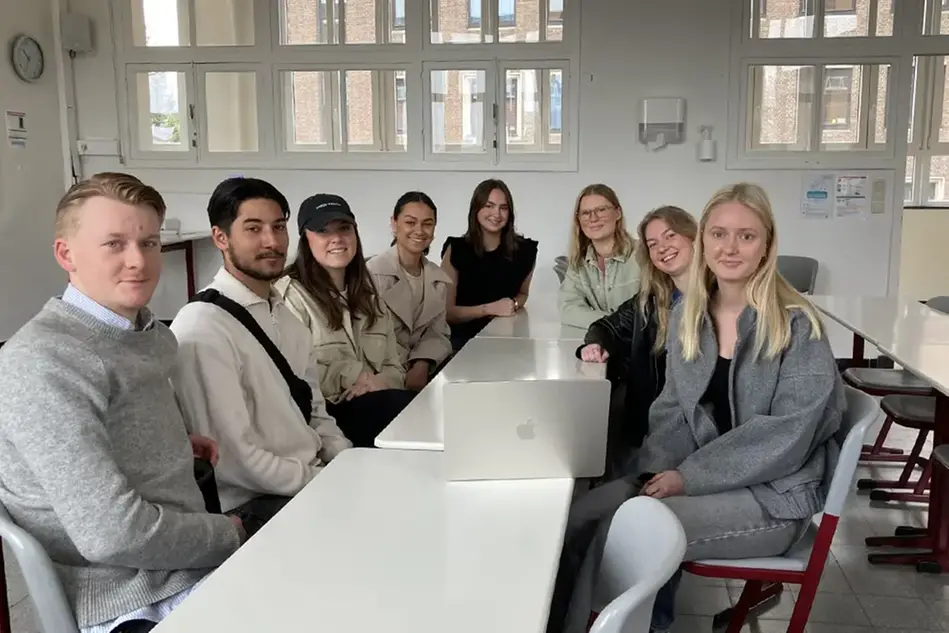 Studenter står på en scen framför publik och pratar. Foto.
