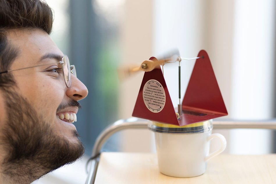 Porträtt av en ung man som tittar på en prototyp av ett vindkraftverk. Foto.