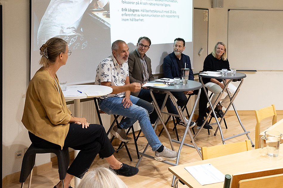 Två kvinnor och tre män sitter framför en presentation i en lektionssal. Foto.