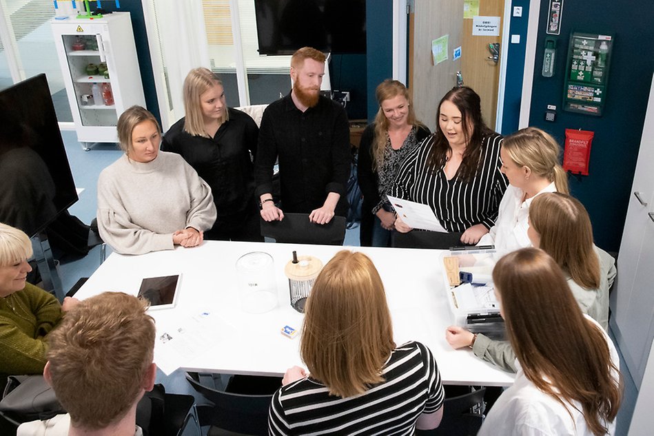 En grupp unga vuxna, studenter, runt ett vitt bord