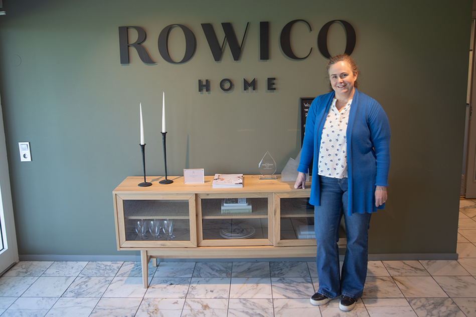 En kvinna står framför en vägg med en logotyp där det står "Rowico Home". Foto.