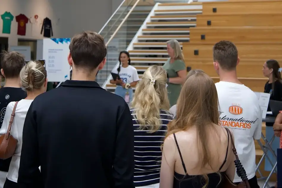 Grupp med personer som står vända med ryggen och lyssnar på två som talar