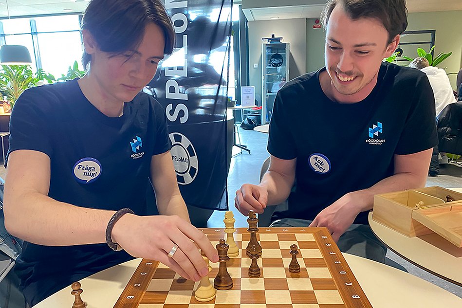 Two people sitting down smiling while playing chess.