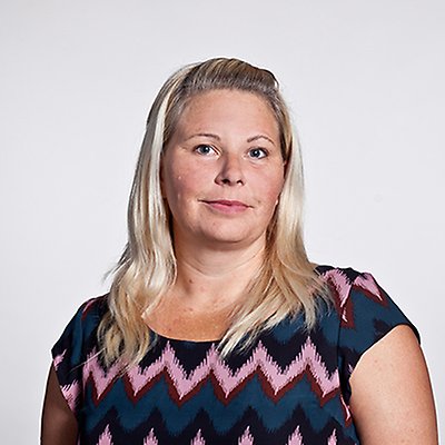 En person med långt ljust hår ser in i kameran. Foto.
