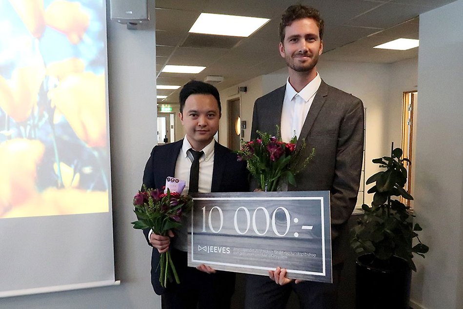 Två finklädda personer håller i var sin blombukett och en skylt med texten 10 000 kronor. Foto.