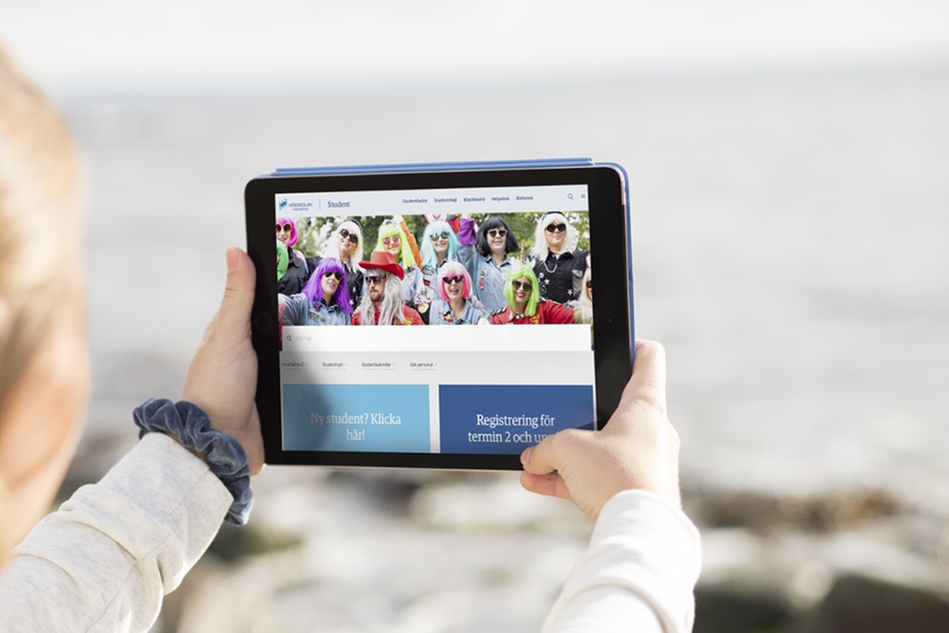En student håller i en Ipad som visar studentwebbens startsida.