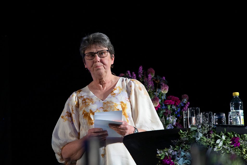 A brightly dressed person standing in a lectern. Photography