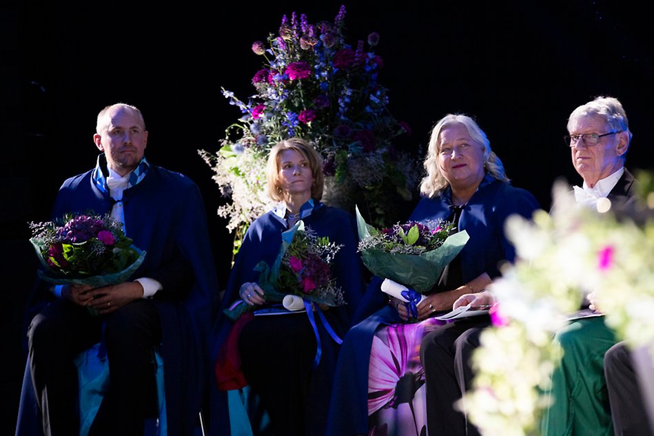 Fyra personer sitter på en scen. Fotografi.