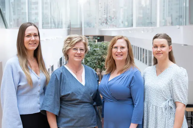Four people in shades of blue smiling at the camera.