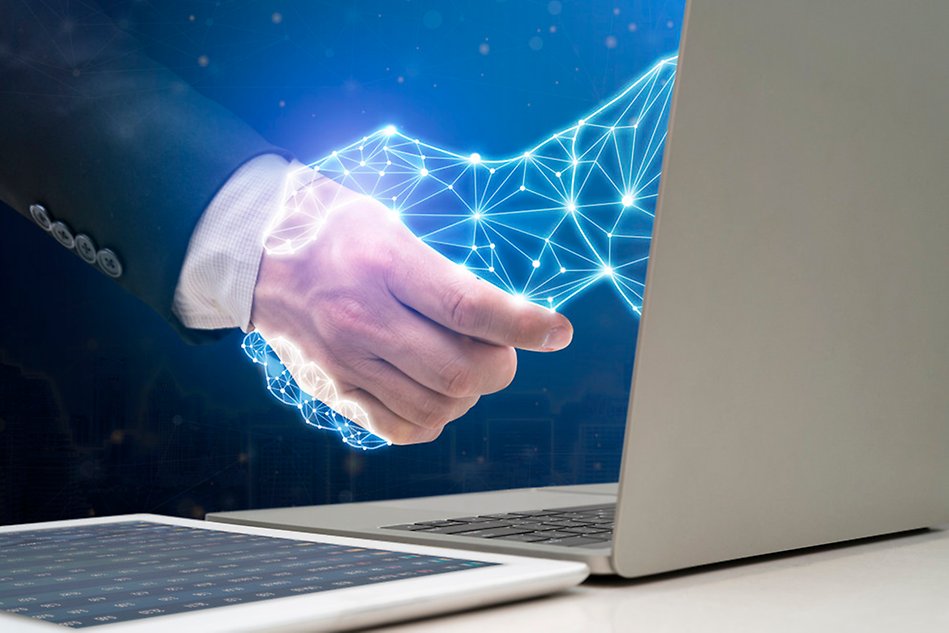 Businessman shaking hands with digital partner extending from laptop computer on futuristic background. Photo/Illustration